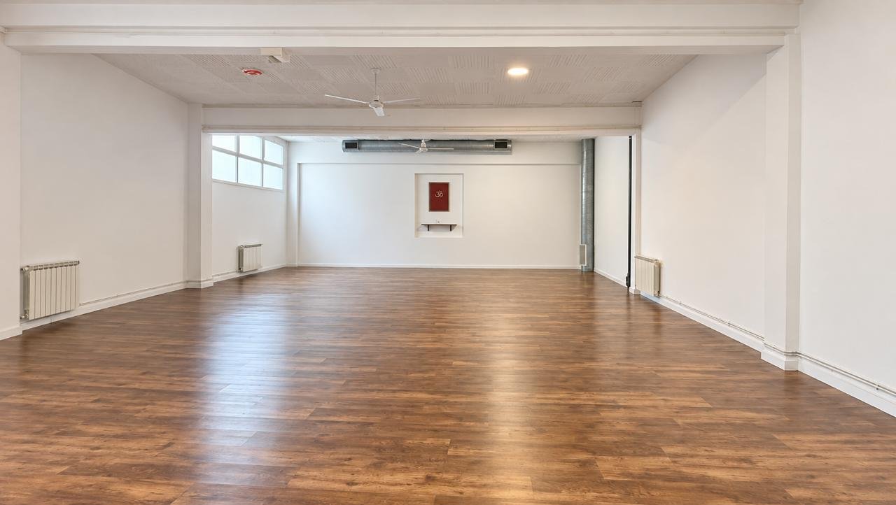 La sala de práctica del Centro: piso de madera, paredes blancas y, al fondo, un cuadro con el símbolo Om